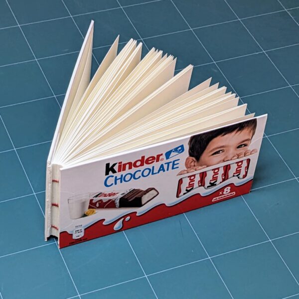 Handmade notebook with upcycled cover of Kinder chocolate package binded by an artist Žilvinas Bražukas Production. Rankų darbo užrašinė su pernaudota Kinder Šokolado pakuote
